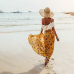 O fată poartă o fustă maxi florală și merge desculță pe malul mării, Thailanda, Phuket. Stil vestimentar boem.