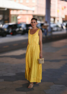 Olivia Palermo este văzută purtând o rochie lungă galbenă Jason Wu, o geantă  din rafie bej și sandale din piele aurie.