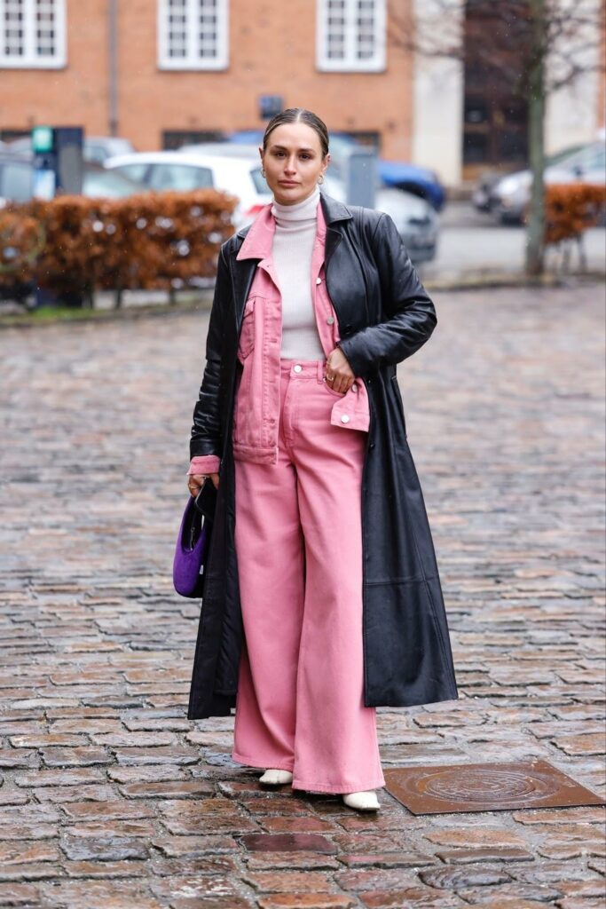 Denim total look roz cu palton negru piele în stil matrix, geantă mov și botine albe