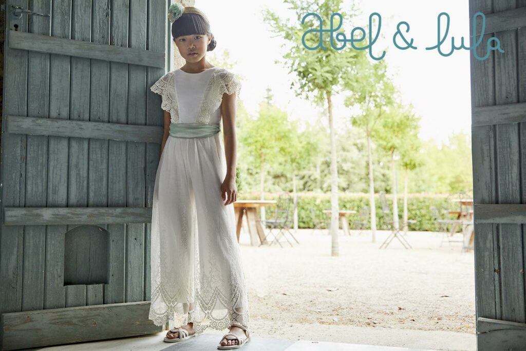 Fetiță într-o rochie albă lungă din dantelă și sandale albe