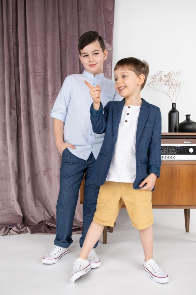 Doi băieți cu cămăși, pantaloni eleganți și teniși Converse