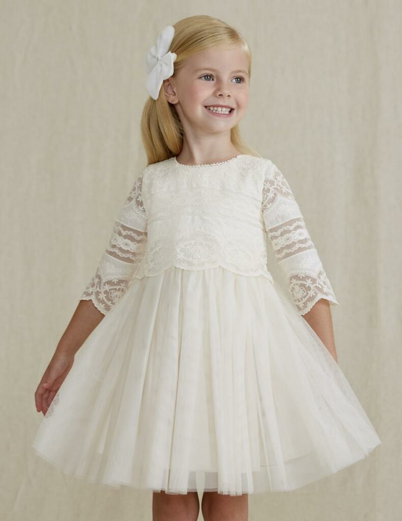 Fetiță cu o rochie albă din dantelă și o fundă albă de păr