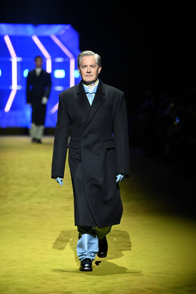 Model care poartă un palton negru lung și pantofi negri cu talpă groasă