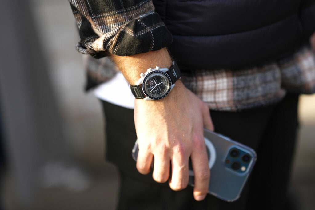 MILAN, ITALY - JANUARY 14: A guest wears a black watch from collaboration Omega x Swatch, outside Jordanluca, during the Milan Menswear Fall/Winter 2023/2024 on January 14, 2023 in Milan, Italy. (Photo by Edward Berthelot/Getty Images)