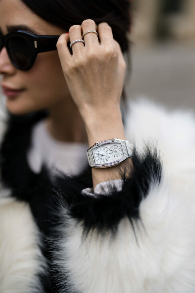 PARIS, FRANCE - DECEMBER 24: Heart Evangelista wears black sunglasses, silver and diamond with emerald pendant earrings, a white with black borders fur jacket, diamonds rings, a white leather and diamonds watch from Philip Stein, during a street style fashion photo session, on December 24, 2022 in Paris, France. (Photo by Edward Berthelot/Getty Images)