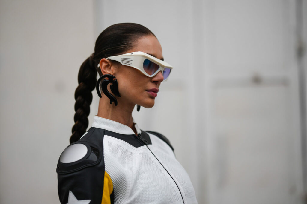 PARIS, FRANCE - JANUARY 23: A guest wears white and orange sunglasses, black oversized plastic earrings, a black / white / yellow print pattern shiny leather zipper high neck jacket from Dior, outside Dior, during Paris Fashion Week - Haute Couture Spring Summer, on January 23, 2023 in Paris, France. (Photo by Edward Berthelot/Getty Images)