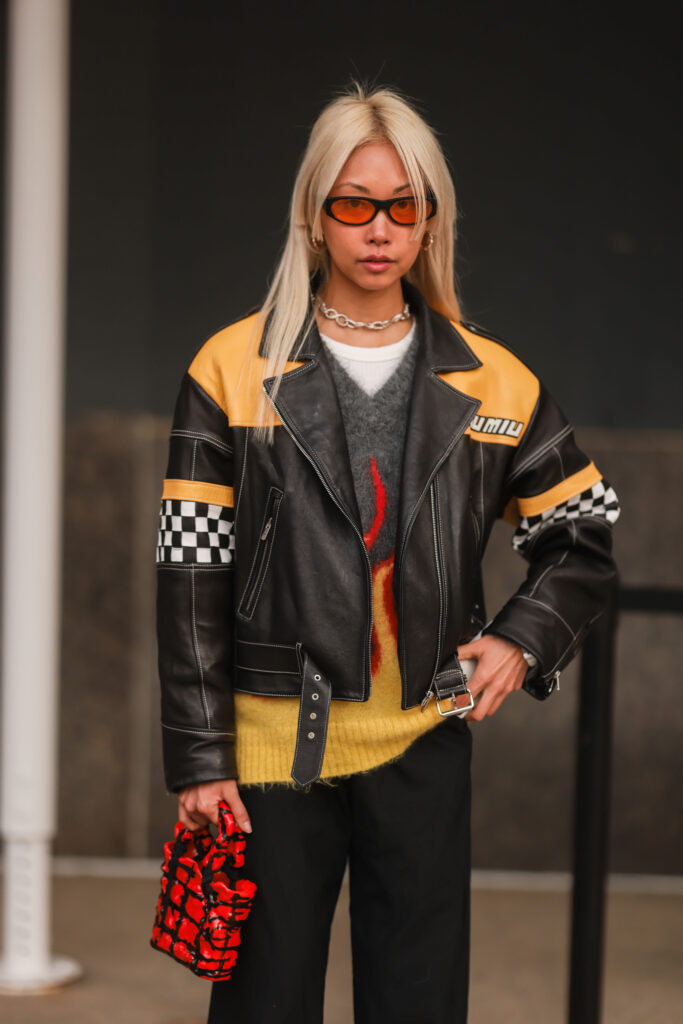 Vanessa Hong poartă o geacă din piele neagră de curse, un pulover din cașmir gri-galben, o geantă mini neagră roșie, pantaloni cu picior larg, ochelari de soare în fața casei Prabal Gurung în timpul Săptămânii modei newyorkeze