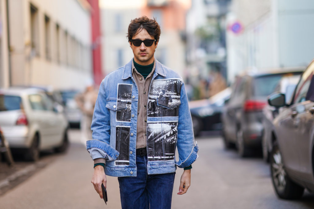 Un bărbat cu o geacă de blugi stilată mergând pe stradă