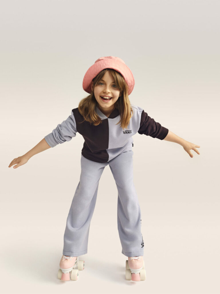 O fată cu trening albastru de la Vans, un bucket hat roz și role