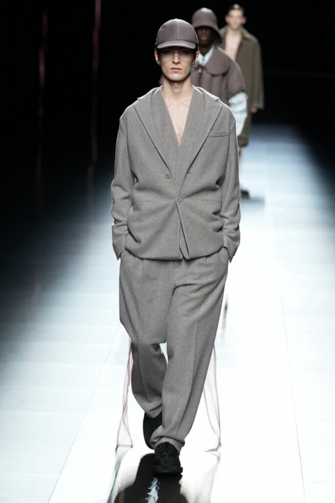 Un model pășește pe podiumul Dior într-un outfit gri