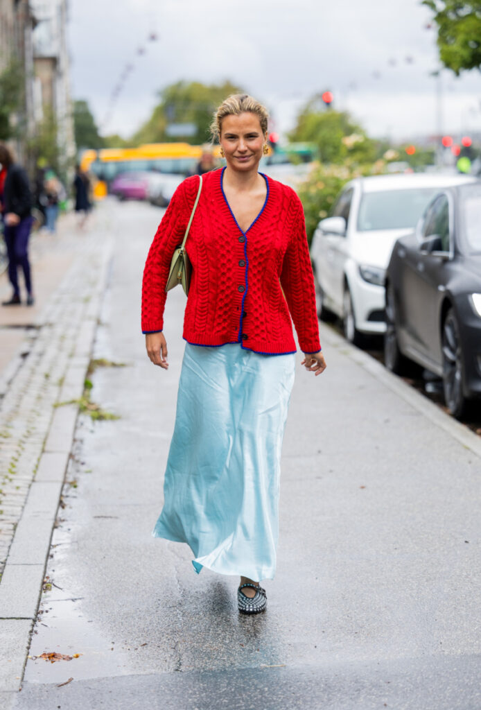 o femeie cu un cardigan roșu și o fustă albastră