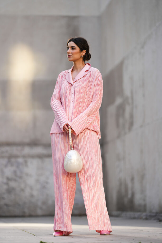 Katie Giorgadze poartă cercei Dior, pantaloni de pijama roz plisată de la J'amemme, o cămașă de pijama roz plisată de la J'amemme și o geantă albă