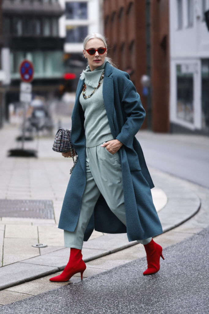 femeie care poartă un palton de culoare petrol și pantofi roșii